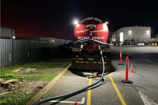Chittering Septic Service tanker cleaning a grease trap at a commercial site at night