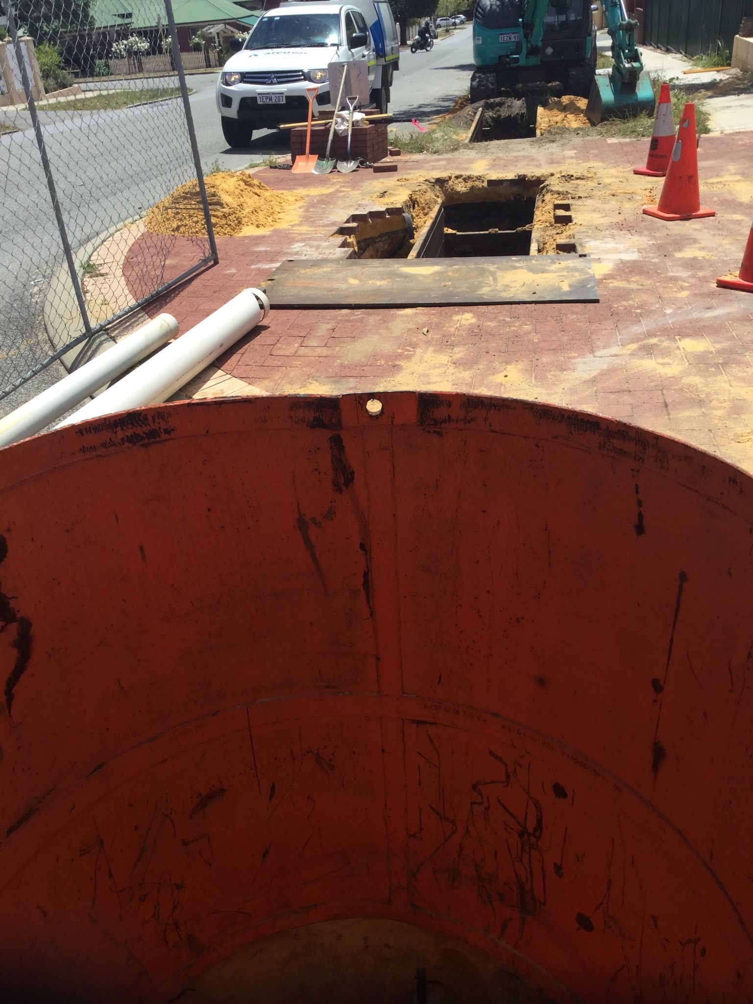 Looking down from the top of the red tanker at an open pit in a paved area